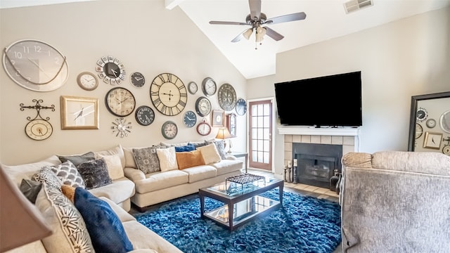 living room with ceiling fan, a tiled fireplace, and lofted ceiling with beams