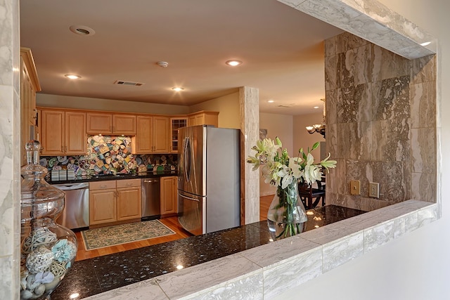 kitchen featuring a chandelier, kitchen peninsula, decorative backsplash, appliances with stainless steel finishes, and light hardwood / wood-style floors