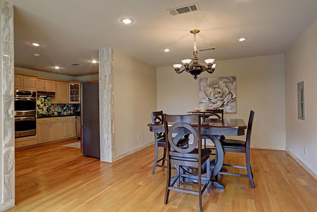 dining room with light hardwood / wood-style flooring and a notable chandelier