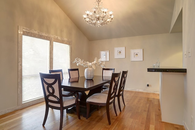 dining space with high vaulted ceiling, a chandelier, and light hardwood / wood-style flooring