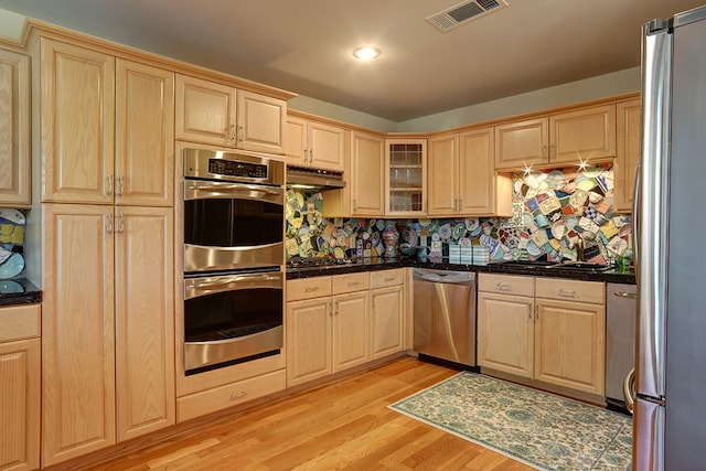 kitchen featuring light wood-type flooring, light brown cabinetry, stainless steel appliances, and decorative backsplash