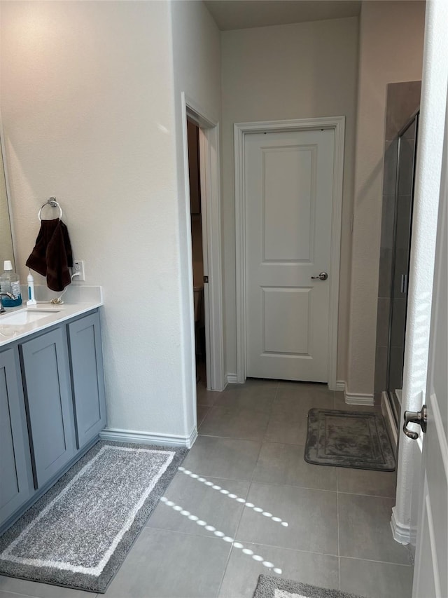 bathroom featuring a shower stall, baseboards, tile patterned flooring, and vanity