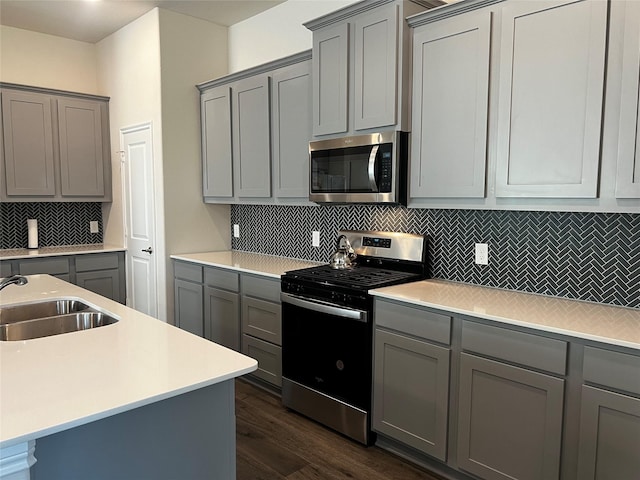 kitchen featuring stainless steel appliances, gray cabinetry, and dark wood-type flooring