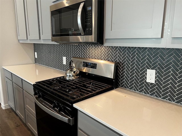 kitchen featuring appliances with stainless steel finishes, gray cabinetry, tasteful backsplash, and light countertops
