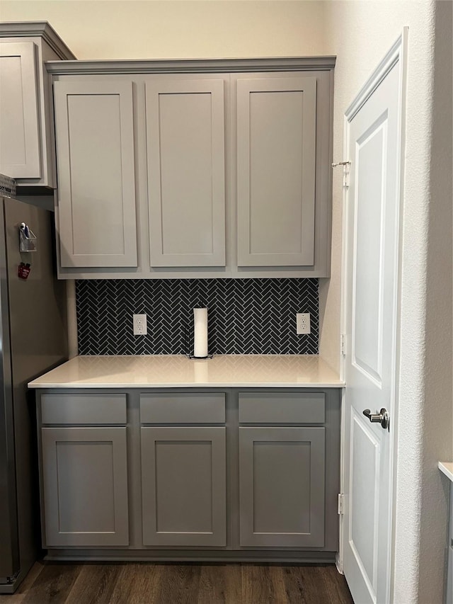 kitchen with gray cabinets, decorative backsplash, dark wood-type flooring, and light countertops
