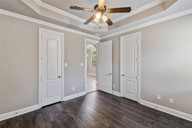 unfurnished bedroom featuring crown molding, dark wood-type flooring, a raised ceiling, and ceiling fan