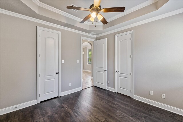 unfurnished room featuring ceiling fan, a tray ceiling, crown molding, and dark wood-type flooring