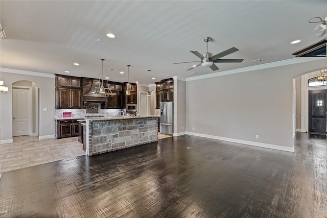 unfurnished living room with crown molding and ceiling fan with notable chandelier