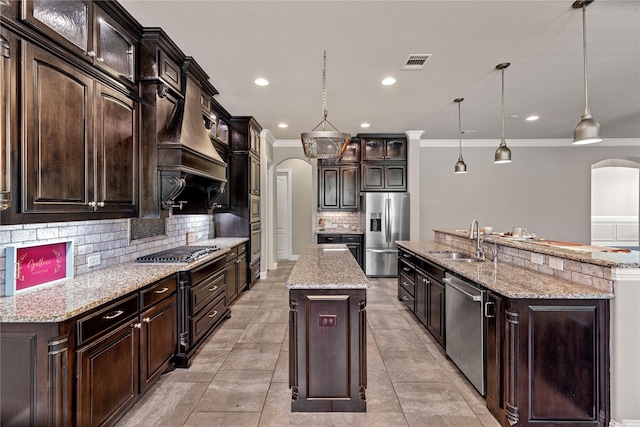 kitchen with appliances with stainless steel finishes, pendant lighting, sink, a kitchen island with sink, and dark brown cabinets