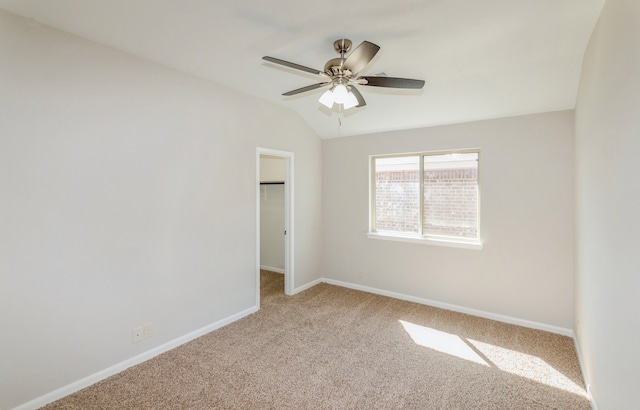 spare room featuring ceiling fan, light carpet, and vaulted ceiling