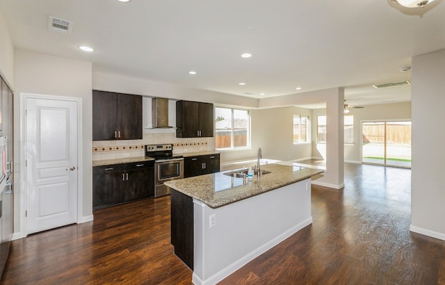 kitchen with a healthy amount of sunlight, stainless steel electric range, sink, wall chimney exhaust hood, and dark brown cabinetry