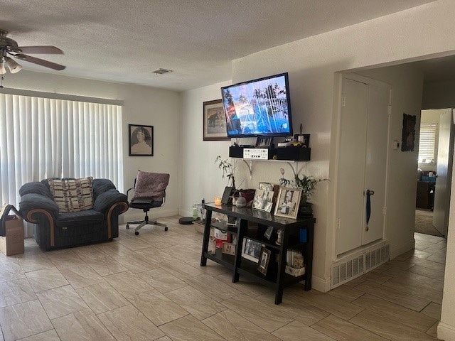 living room featuring ceiling fan and a textured ceiling