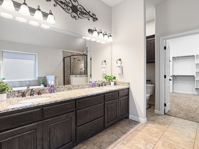 bathroom with tile patterned floors, vanity, toilet, and a shower with shower door