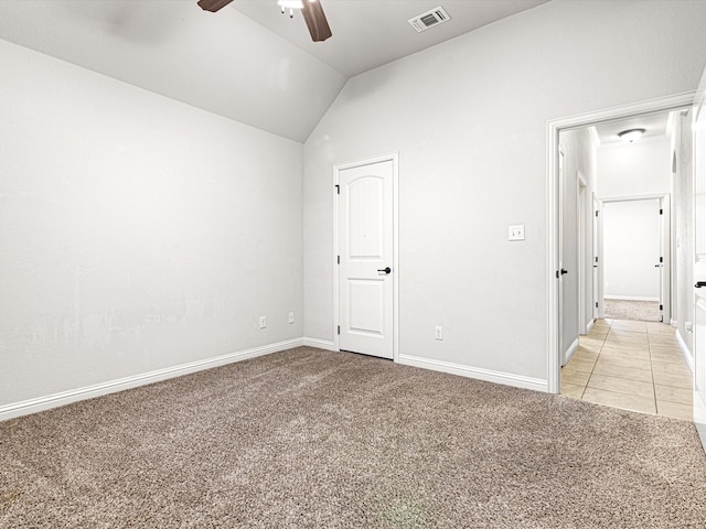 empty room with vaulted ceiling, light colored carpet, and ceiling fan