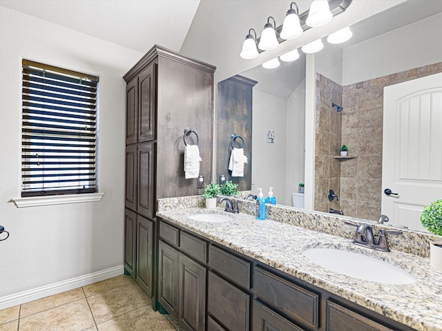 bathroom with vanity, toilet, tiled shower, and tile patterned floors