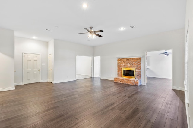 unfurnished living room featuring dark hardwood / wood-style floors, ceiling fan, and a brick fireplace