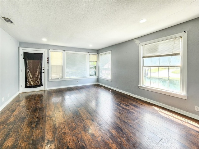 unfurnished living room featuring dark hardwood / wood-style flooring and a textured ceiling