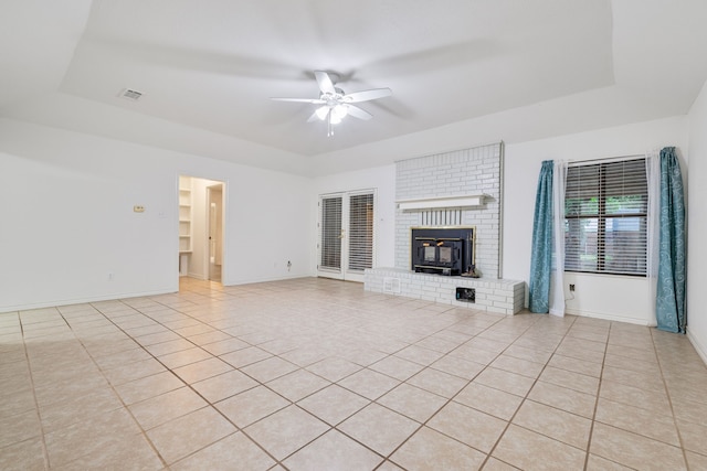 unfurnished living room with ceiling fan, a raised ceiling, and light tile patterned floors