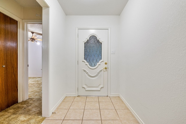 entryway with ceiling fan, light tile patterned floors, and a textured ceiling