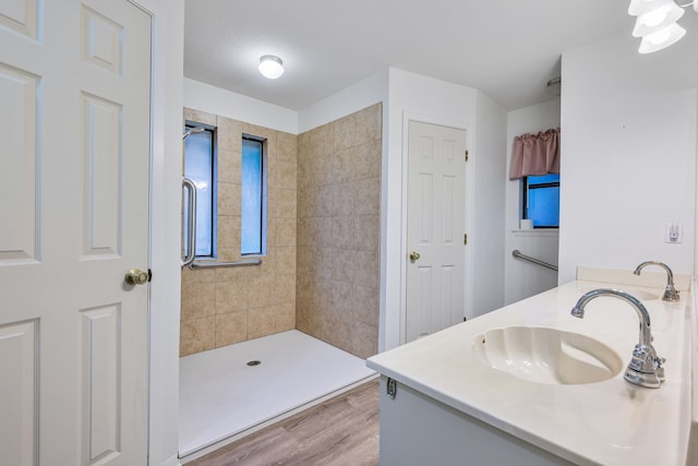 bathroom featuring a textured ceiling, hardwood / wood-style flooring, vanity, and tiled shower