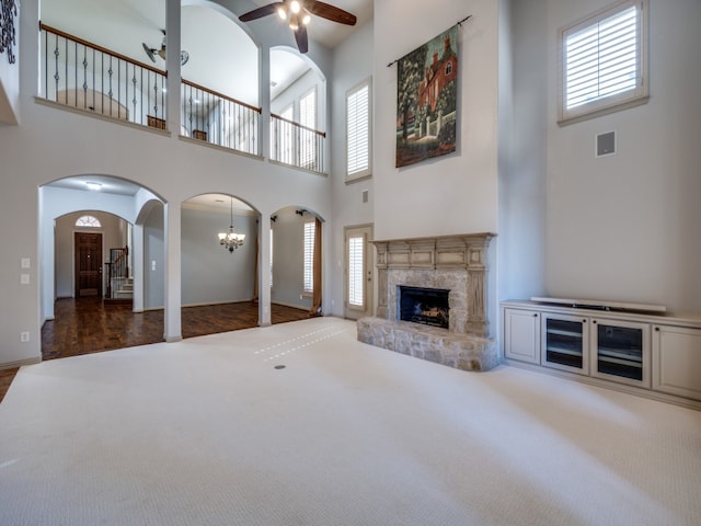 unfurnished living room with a healthy amount of sunlight, ceiling fan with notable chandelier, and a fireplace