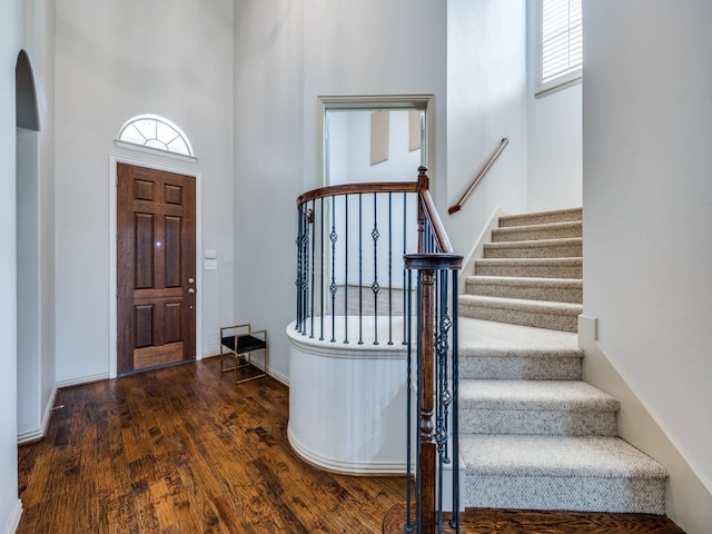 foyer entrance with dark hardwood / wood-style floors and a towering ceiling