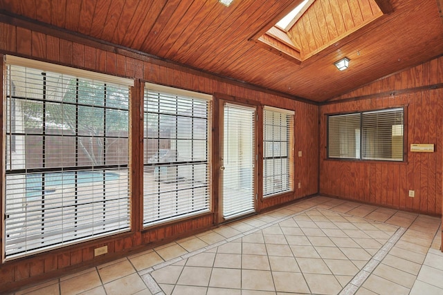 tiled spare room featuring a wealth of natural light, wooden walls, wooden ceiling, and a skylight