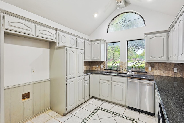 kitchen with dark stone countertops, high vaulted ceiling, backsplash, sink, and stainless steel dishwasher