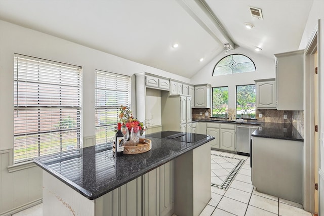 kitchen featuring dark stone counters, tasteful backsplash, a center island, stainless steel dishwasher, and gray cabinetry