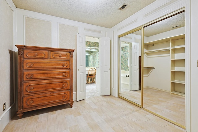 unfurnished bedroom with a textured ceiling, light hardwood / wood-style flooring, and a closet