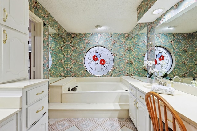 bathroom with a washtub, a textured ceiling, and vanity