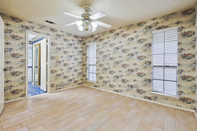 spare room featuring a textured ceiling, light hardwood / wood-style flooring, and ceiling fan