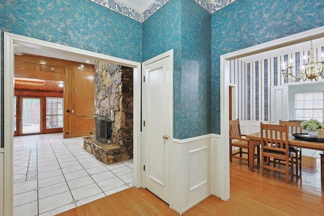 corridor with a high ceiling, an inviting chandelier, and light wood-type flooring