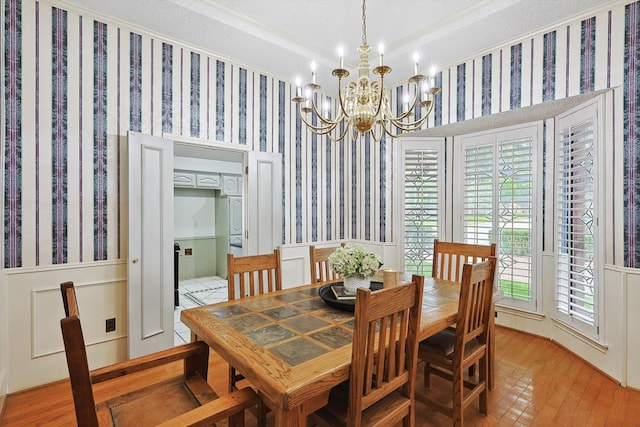 dining room with crown molding, a healthy amount of sunlight, an inviting chandelier, and light wood-type flooring