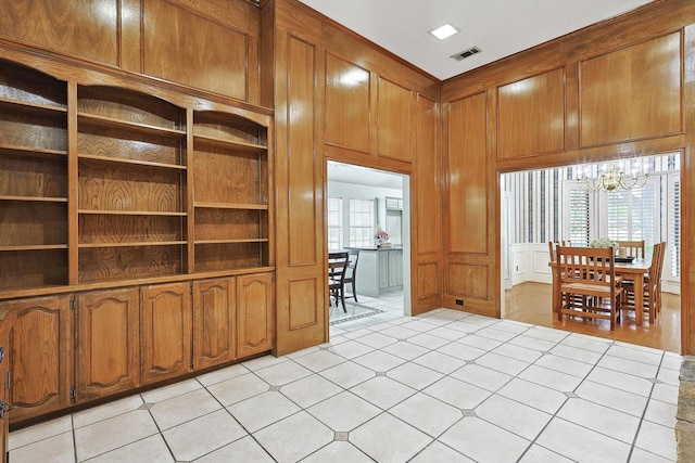 interior space featuring wood walls, light tile patterned floors, and a notable chandelier