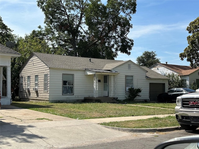 ranch-style house featuring a front yard, a garage, and roof with shingles