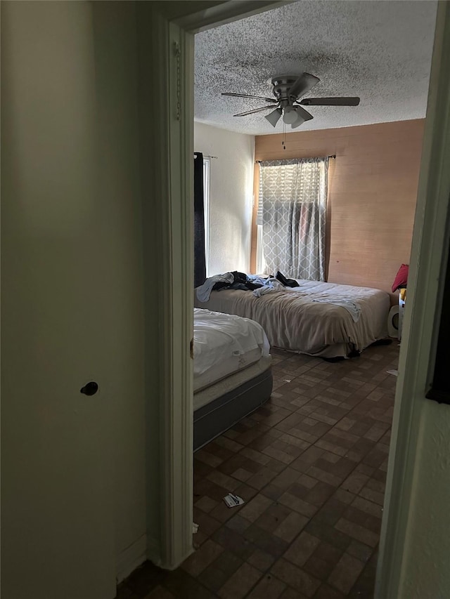 bedroom with a textured ceiling, brick floor, and a ceiling fan