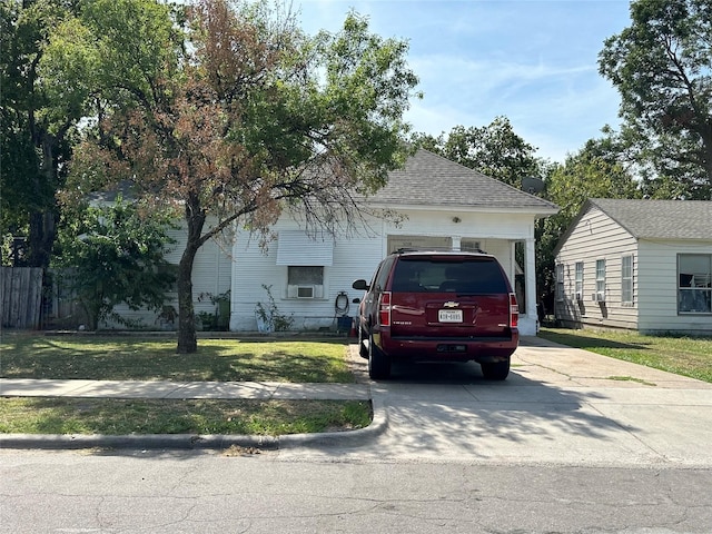 view of front of house featuring a front yard, concrete driveway, and roof with shingles