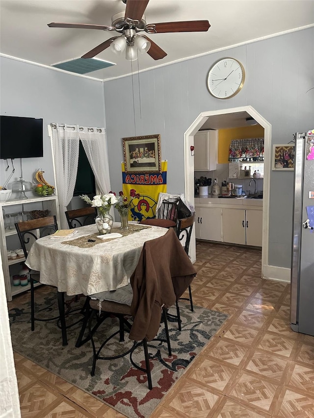 dining room featuring wooden walls, crown molding, light parquet flooring, and ceiling fan