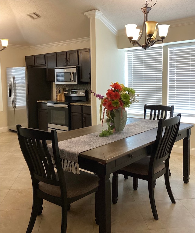 tiled dining space with ornamental molding, a chandelier, and a textured ceiling