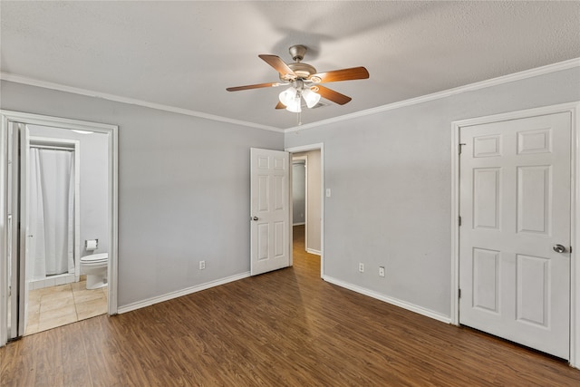 unfurnished bedroom featuring ensuite bath, ceiling fan, dark hardwood / wood-style floors, a textured ceiling, and ornamental molding