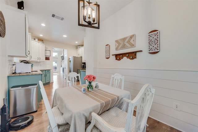 dining room with light hardwood / wood-style flooring and an inviting chandelier