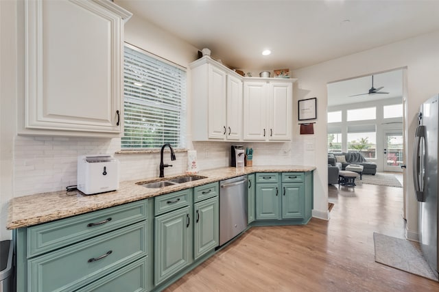 kitchen featuring sink, ceiling fan, appliances with stainless steel finishes, white cabinets, and light hardwood / wood-style floors