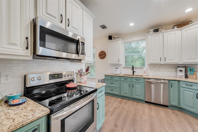 kitchen with green cabinets, light hardwood / wood-style flooring, sink, appliances with stainless steel finishes, and white cabinets