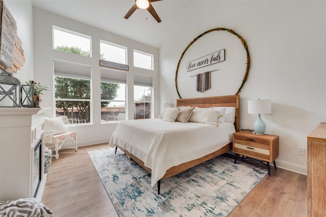 bedroom featuring a towering ceiling, ceiling fan, and light hardwood / wood-style flooring