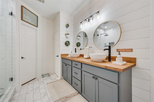 bathroom featuring a shower with shower door, wood walls, and vanity