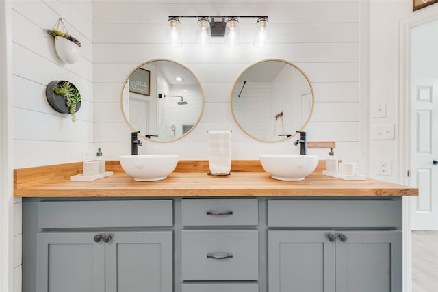 bathroom featuring vanity, wood walls, wood-type flooring, and a shower