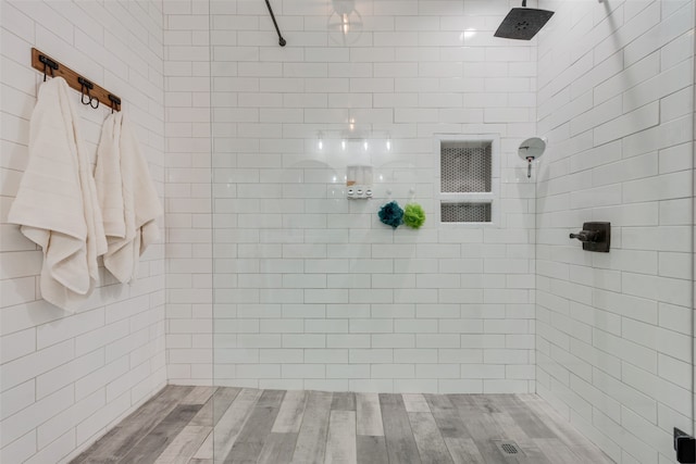 bathroom with hardwood / wood-style flooring and a tile shower