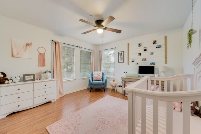 bedroom featuring ceiling fan, a nursery area, and light hardwood / wood-style flooring