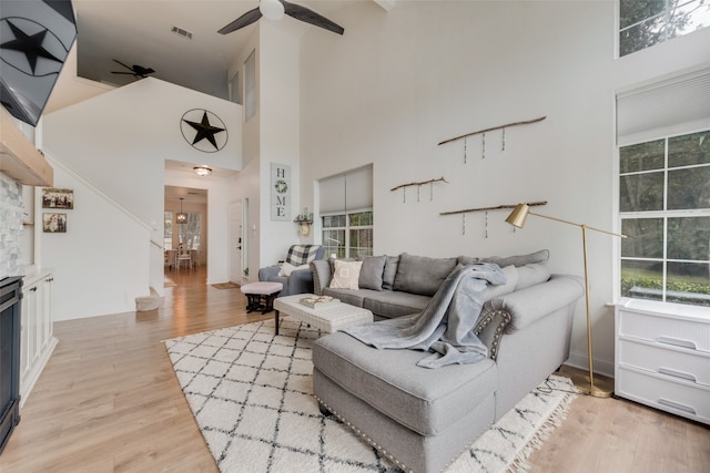 living room featuring light hardwood / wood-style flooring, ceiling fan, and a high ceiling